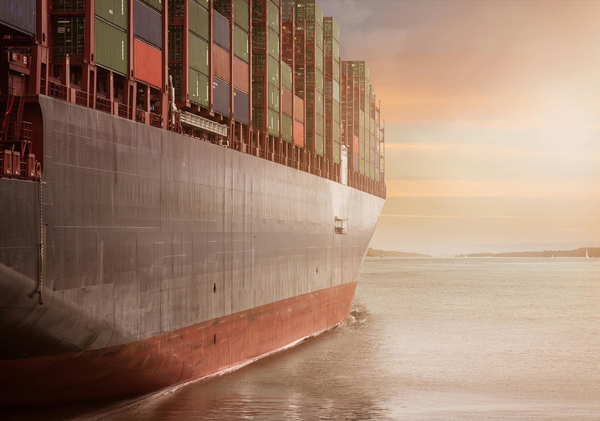 Loaded container vessel leaving port at dawn